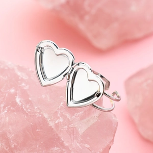 Detailed view of silver heart locket ring on pink crystal with open compartment