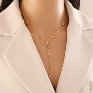 Long gold Y-shaped heart necklace with minimalist bar accents on a female model