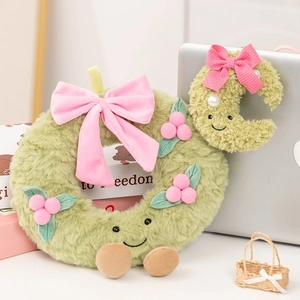 Detail of plush Christmas wreath and moon toys with pink bows on a cozy desk setting