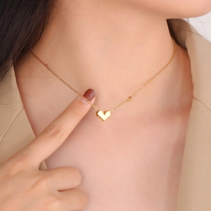Collier avec pendentif cœur 3D doré en acier titane porté par un modèle