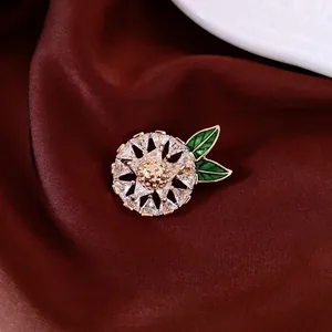 14K gold plated hollow brooch with starburst design, sparkling crystals and green enamel leaves