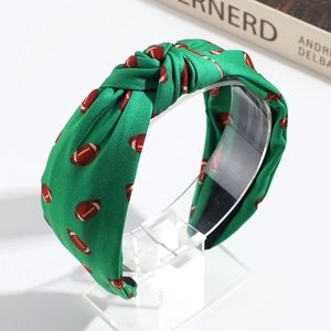 Detailed close-up of a green fabric headband with brown football pattern and knotted design