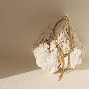 Three-layer gold-plated stainless steel fringe bracelet on a white stone background