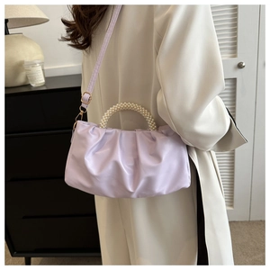 Detail of lavender pleated handbag with pearl handle and matte leather finish on a model