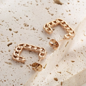 Detailed macro view of rose gold Cuban link hollow rectangular earrings on stone
