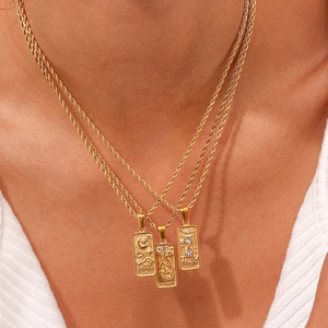 Close-up of layered gold tarot pendant necklaces including The Moon and Strength designs