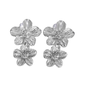 Detail view of silver metal floral double-drop earrings with textured glossy finish