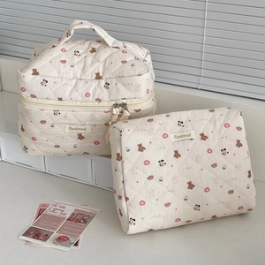 Detail of cream quilted bear print makeup bags with zipper and sturdy top handle