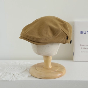 Détail d'une casquette gavroche en coton kaki avec boucle en métal sur une tête de mannequin