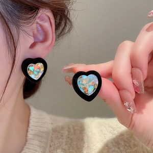Detail of vintage black heart earrings featuring iridescent center stones on model