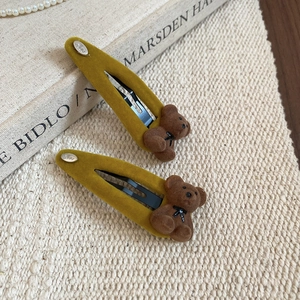 Detail of mustard yellow flocking bear hair clips with black bow on a vintage background