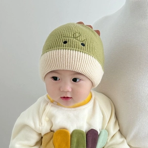 Detailed knit texture of green baby beanie with cute dinosaur back fin and eyes