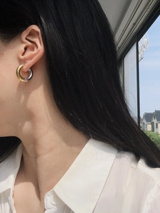 Close-up of model wearing two-tone gold and silver titanium steel hoop earrings