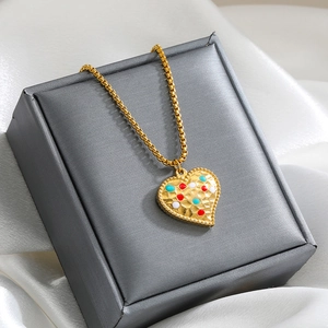 Macro shot of gold heart pendant with colorful enamel texture on dark jewelry box