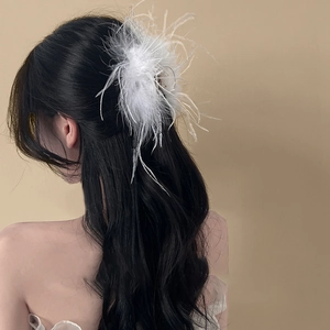 Elegant white ostrich feather hair claw clip on model's wavy dark hair