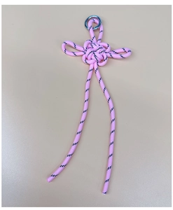 Close-up of pink braided Chinese knot pendant with black spots and silver metal ring