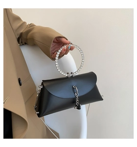 Detail of black jelly bag featuring crystal-studded ring handle and metal chain tassels