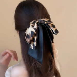 Detail of leopard print fabric hair claw clip with rhinestones worn on a woman's hair