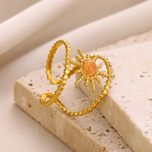 Detail of bohemian gold double ring with orange gemstone and star pattern on stone base