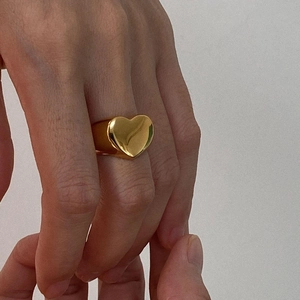Elegant gold hollow heart signet ring in chain style worn on a hand with soft lighting