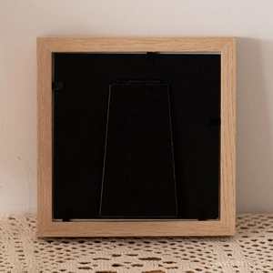 Square wooden 4-inch picture frame with back stand and metal clips on lace fabric