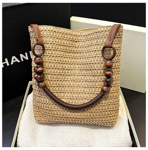 Detail of hand-woven straw bucket bag featuring a wooden ring handle and bead accents