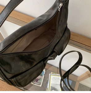 Detail of dark brown vintage faux leather shoulder bag with zipper and multiple pockets