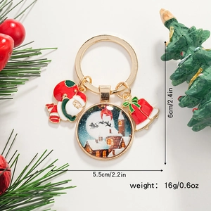 Détail d'un porte-clés de Noël avec Père Noël, village enneigé et clochette rouge