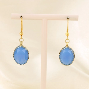 Detail of elegant oval blue faceted glass drop earrings with gold-plated hooks on a stand