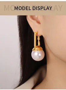 Gros plan de boucles d'oreilles dorées rectangulaires avec perles blanches sur modèle
