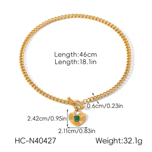 Detail of gold Cuban chain necklace with green zircon heart pendant and toggle clasp