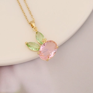 Close-up of golden necklace with a cute pink rabbit pendant on white ceramic plate