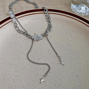 Detail of silver necklace with cat eye opal cloud and star pendants on ceramic plate