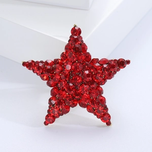 Macro shot of red crystal encrusted star brooch with gold metallic setting details
