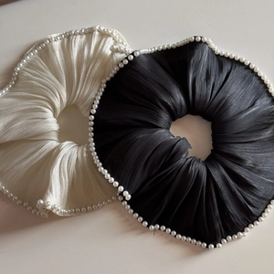 Detail of mercerized yarn scrunchies in black and beige with elegant pearl trim edges