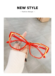 Detail showing red cat-eye glasses frame with yellow accents in a lifestyle hand-held view