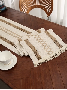 Detail of woven table runner with dual-tone cotton fringe on a dark wood table