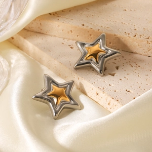 Detailed shot of star earrings in silver and gold two-tone finish on satin background