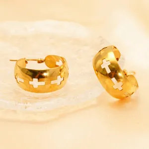 Golden wide hoop earrings featuring hollow cross design on textured glass tray