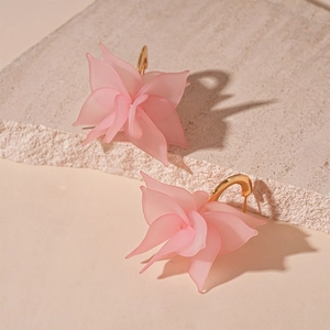 Detail shot of matte pink acrylic flower earrings with golden C-shape metal hooks