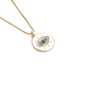 Macro shot of gold-plated evil eye pendant with blue enamel and zircon details