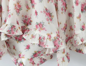 Detail of pink floral print chiffon fabric with delicate ruffle layers and soft texture