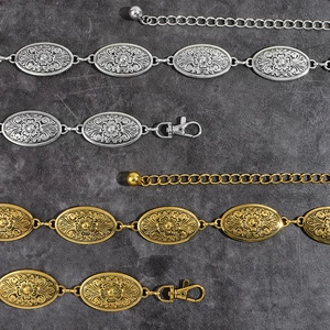 Detail of vintage metal waist belts in gold and silver with carved floral patterns