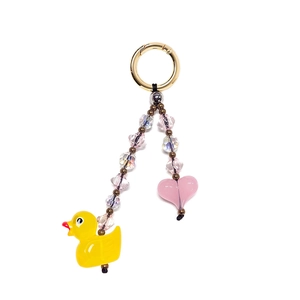 Macro detail of yellow duck and pink heart charm with colorful beads on a gold keychain