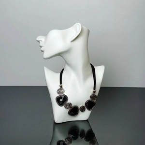 Detail shot of a bohemian multi-layered necklace with black gems on a white mannequin torso