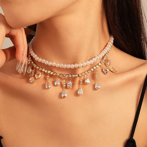 Double-layered gold-tone necklace with white imitation pearls and a colorful teardrop gem