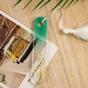 Detail of gradient resin bookmark with dried grass, white tassel and travel text