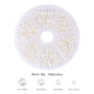 Macro view of assorted white faux pearls in storage box showing four sizes for DIY jewelry