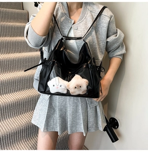 Detail of black PU leather shoulder bag with clear PVC window and plush star charms