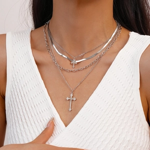 Close-up of layered silver cross pendant necklace with rhinestones on model neck